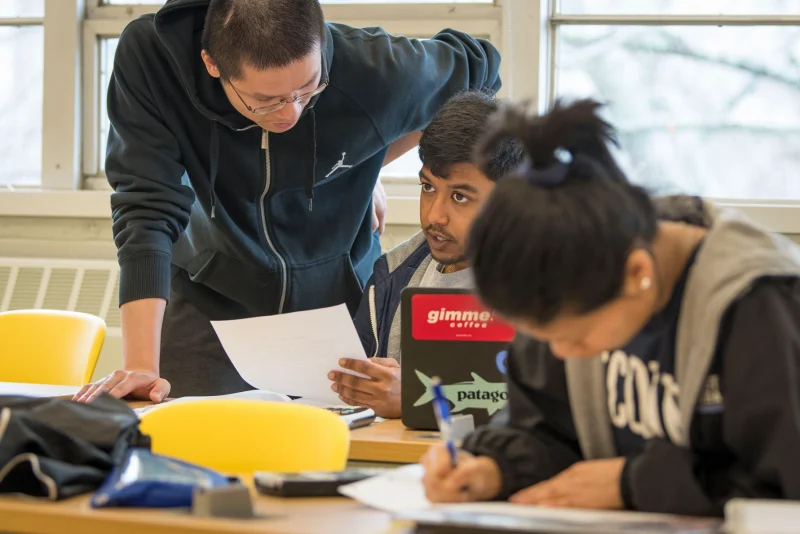 Asian male faculty member assisting diverse student body.