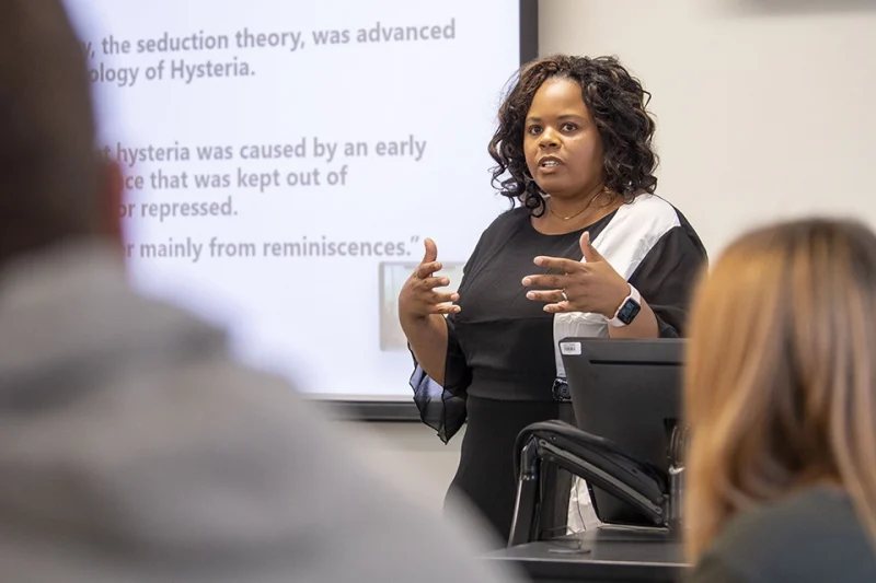 UConn School of Social Work faculty female of color lecturing in classroom.